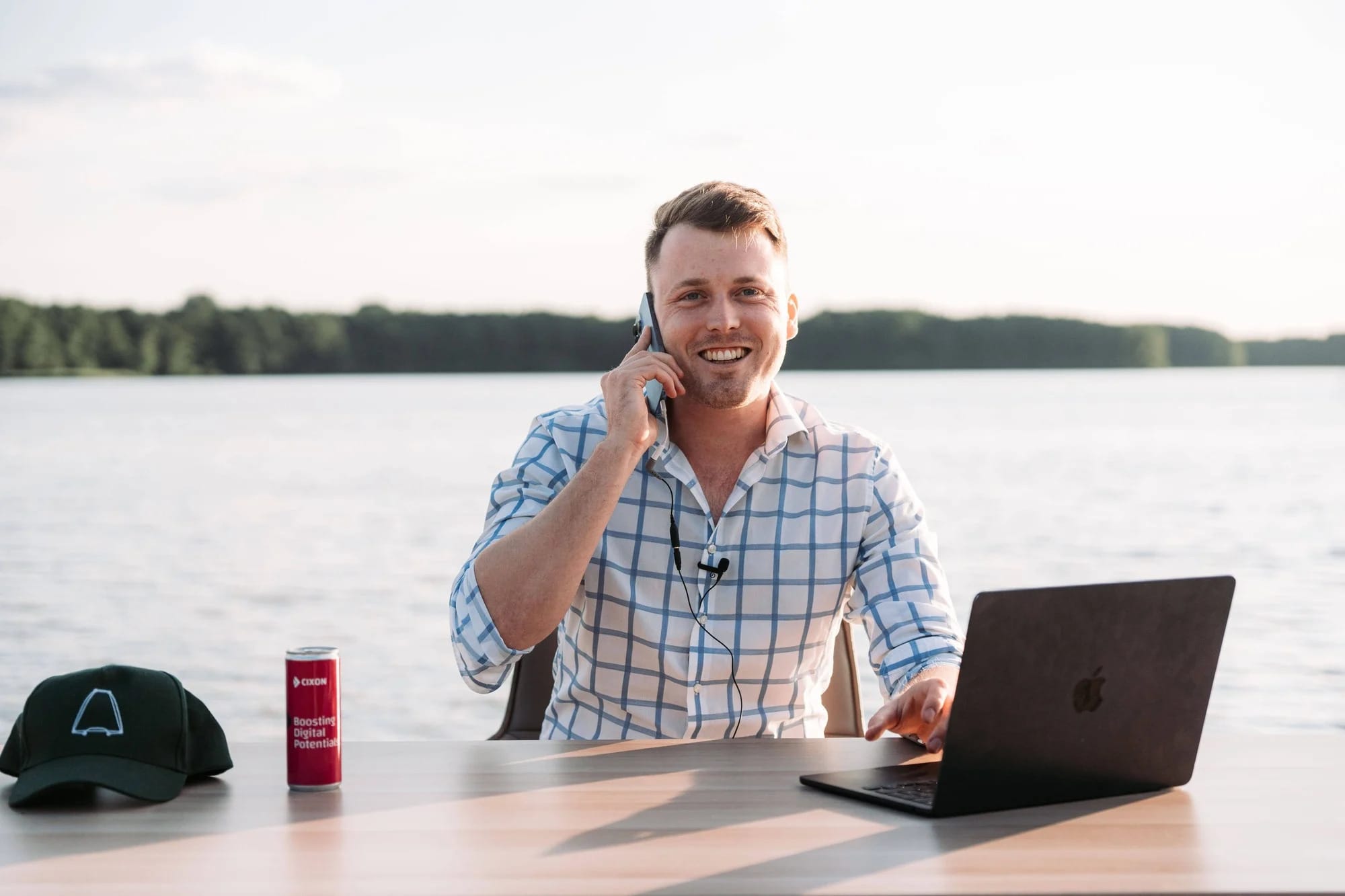 CIXON-Team-Workation-Freizeit-und-Arbeit-Teamevent-Person-an-Schreibtisch-am-Wasser-mit-Telefon-und-