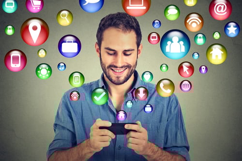 Datenschutz und Transparenz im CRM - Mann schaut auf sein Handy und lacht - Aus dem Handy kommen viele unterschiedliche Symbole in verschiedenen Farben